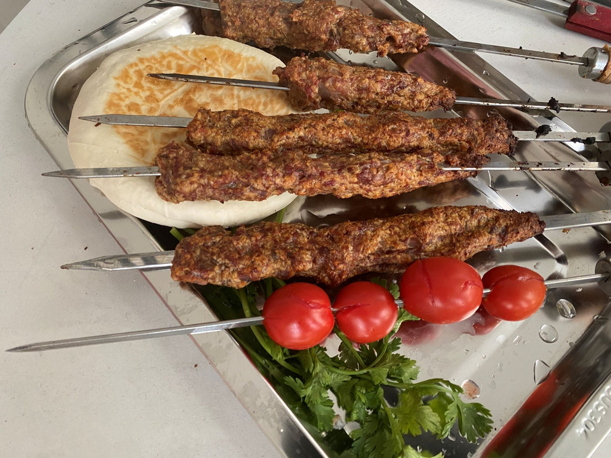 cooked beef kebabs with small potatoes and bread