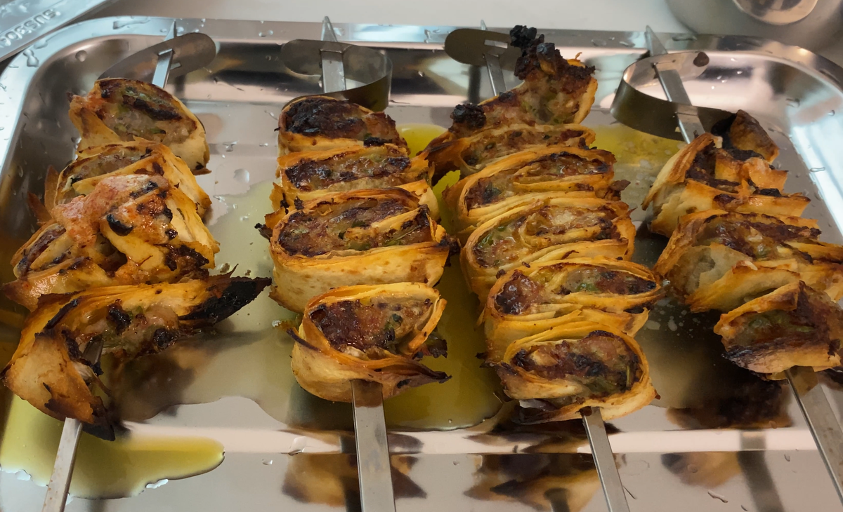 Cooked tortilla pinwheels placed on the stainless food tray