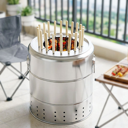 A vertical charcoal grill is shown on a tiled floor of a balcony, with a gray camping chair and a table with skewers.