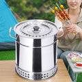 A close-up view of a stainless steel vertical charcoal grill, and a woman in the background holding skewers at a campsite.